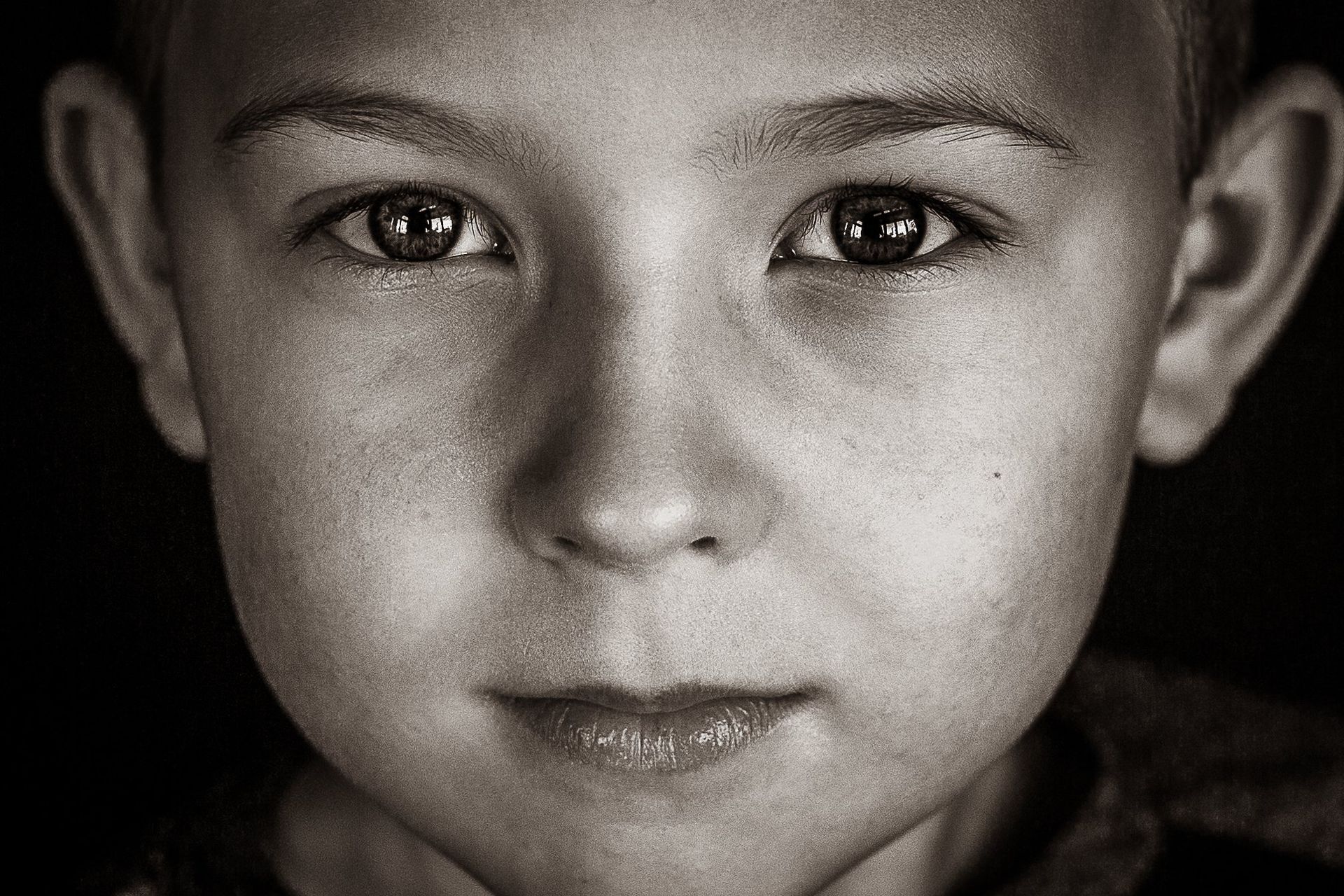 A close up of a young boy 's face in a black and white photo.