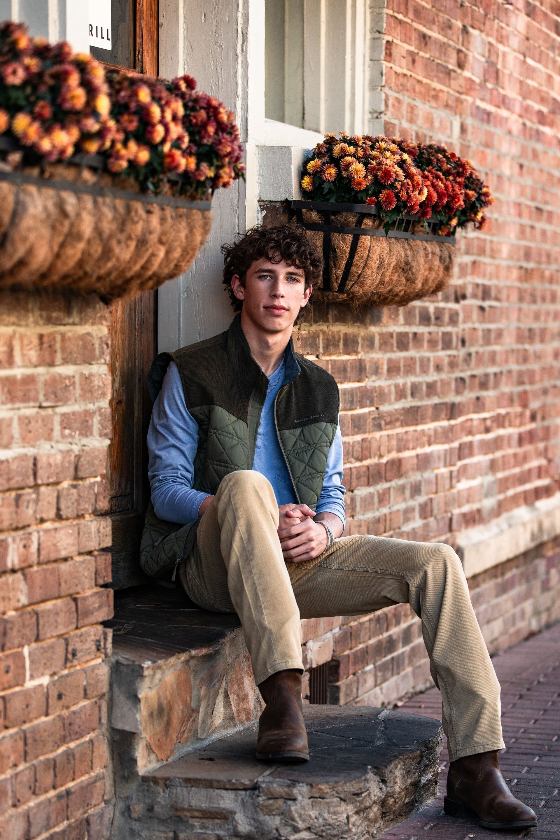 A young man is sitting on the steps of a brick building.