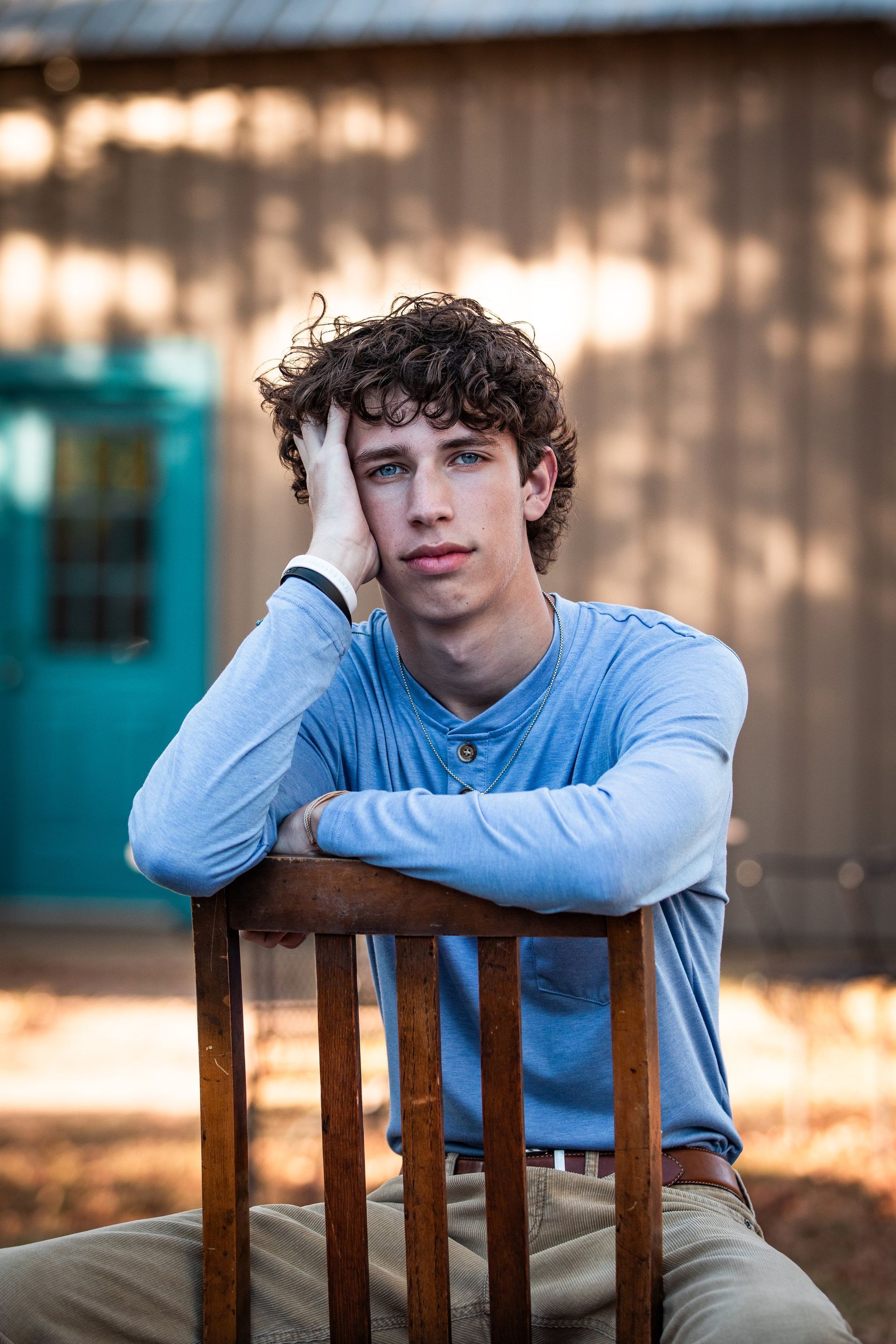 A young man is sitting in a chair with his hand on his head.