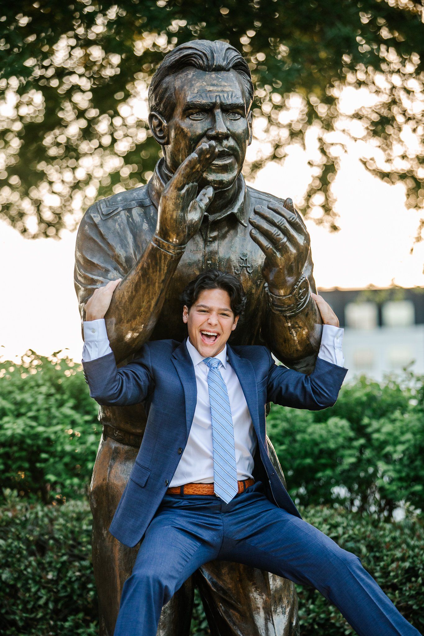 A man in a suit and tie is standing next to a statue of a man.