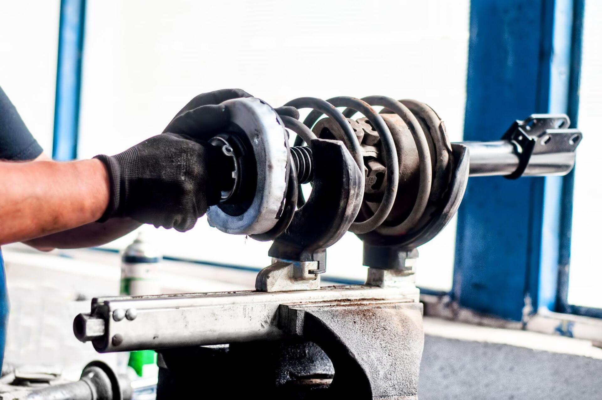 A man is working on a shock absorber in a garage.