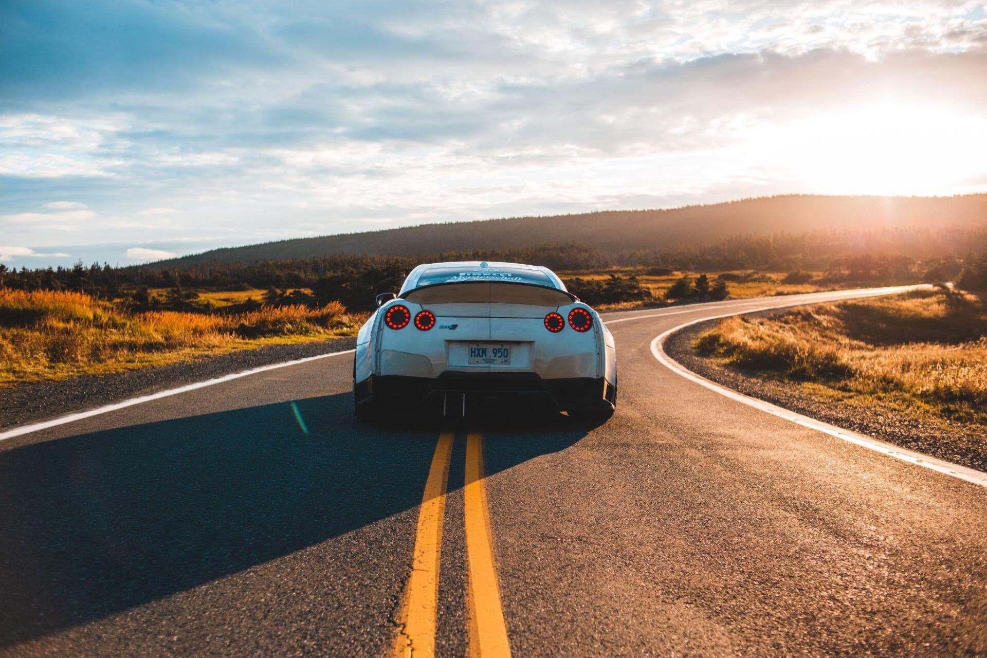 A white sports car is driving down a curvy road.