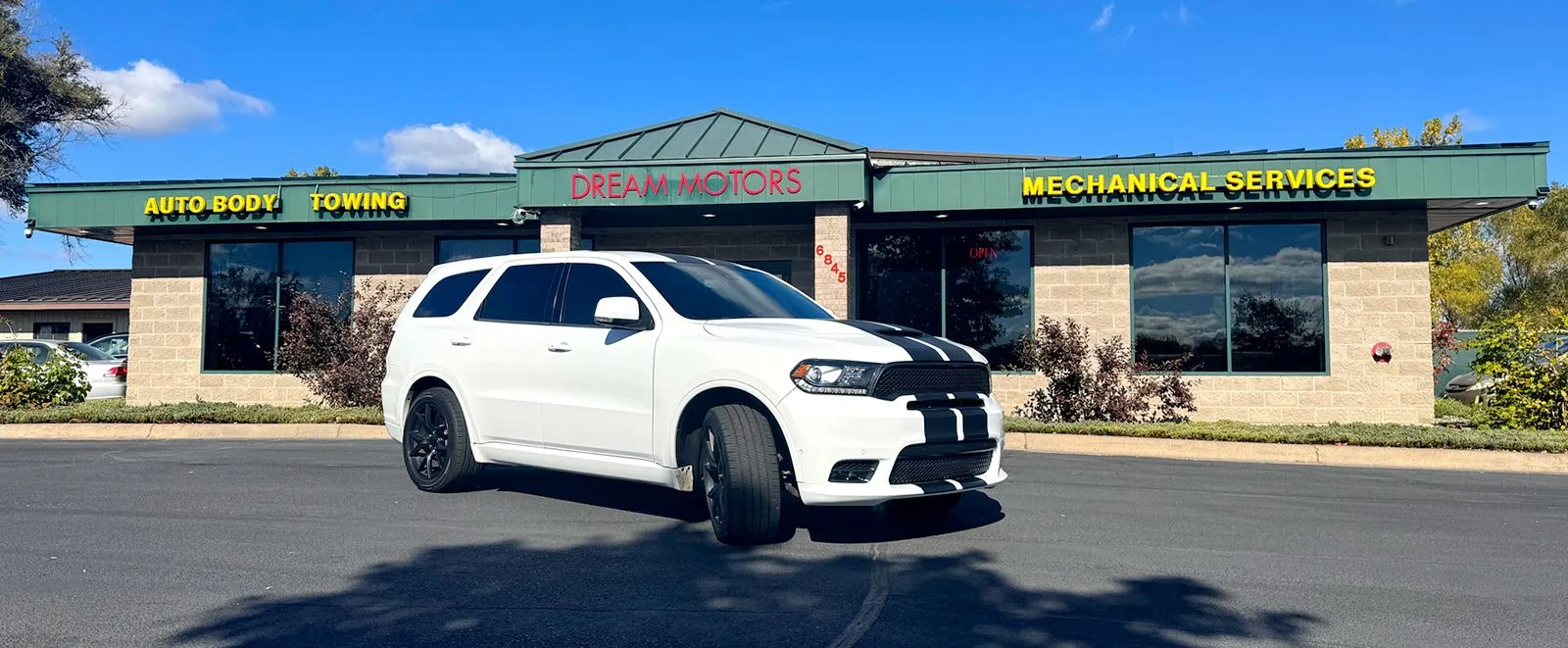 A white dodge durango is parked in front of a building.