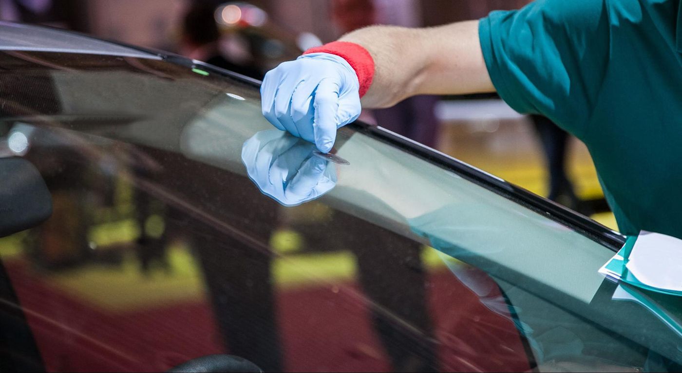 A person is repairing a windshield on a car.