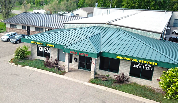 An aerial view of a building with a green roof and cars parked in front of it.