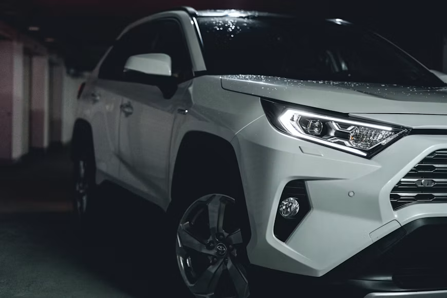 White SUV parked in a dark garage, front-left view with headlights and grille visible