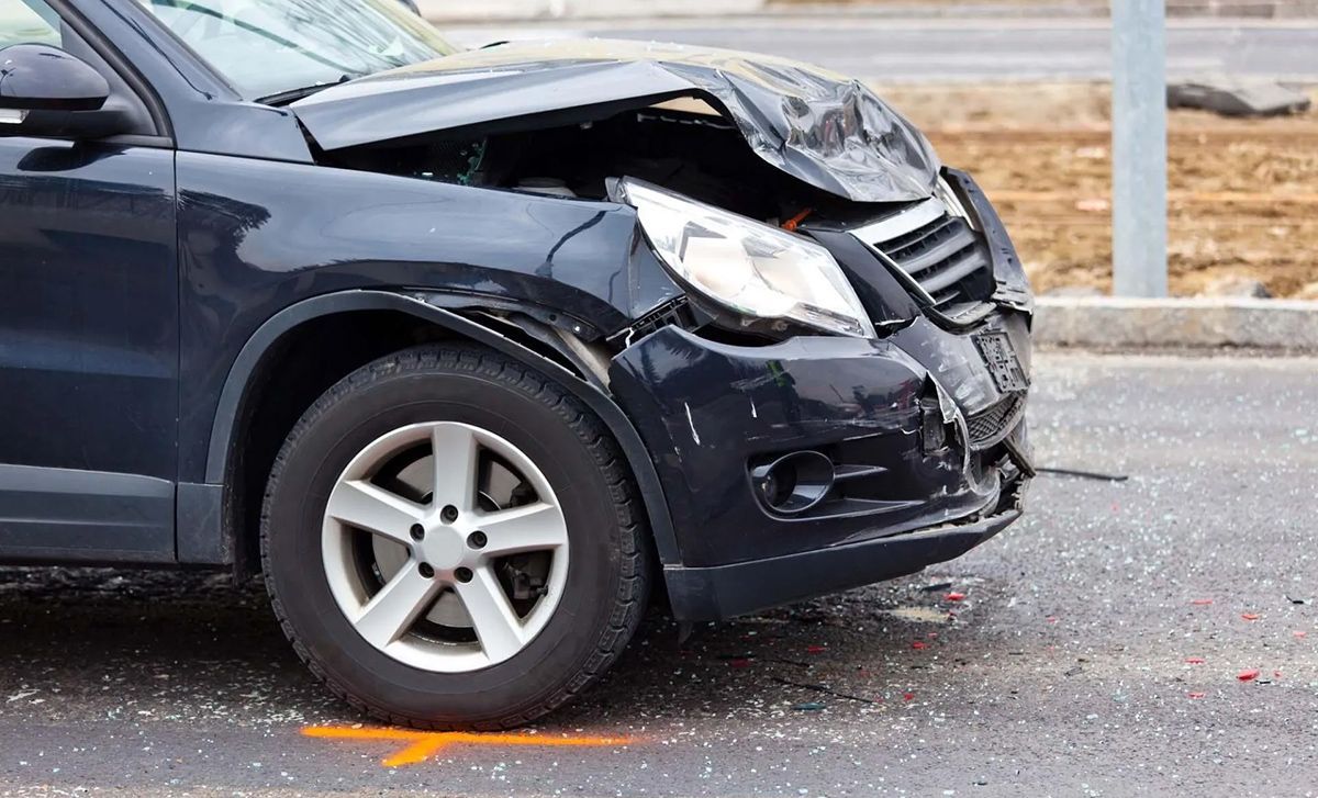 A car with a damaged front end is parked on the side of the road.