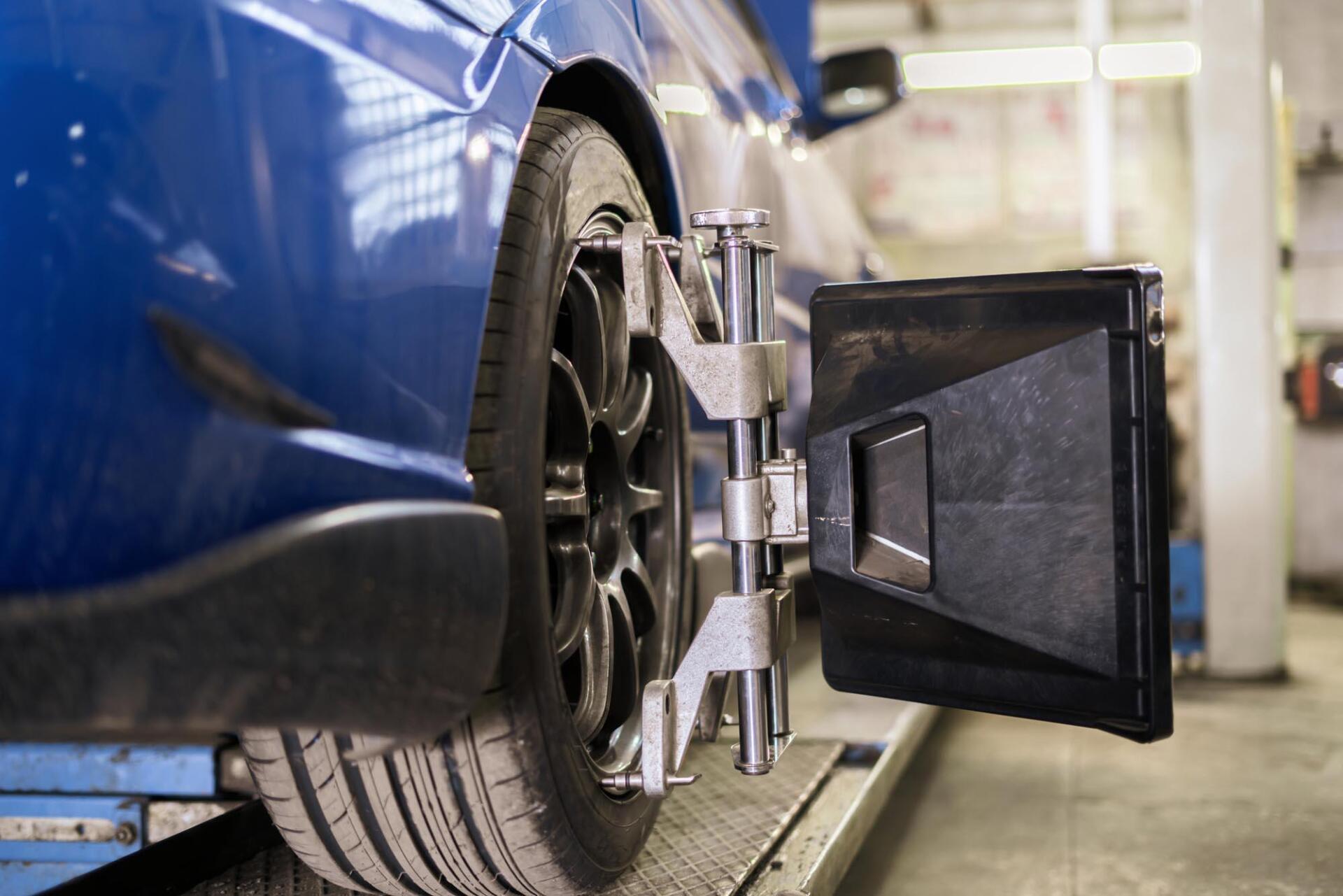 A blue car is being adjusted by a machine in a garage.