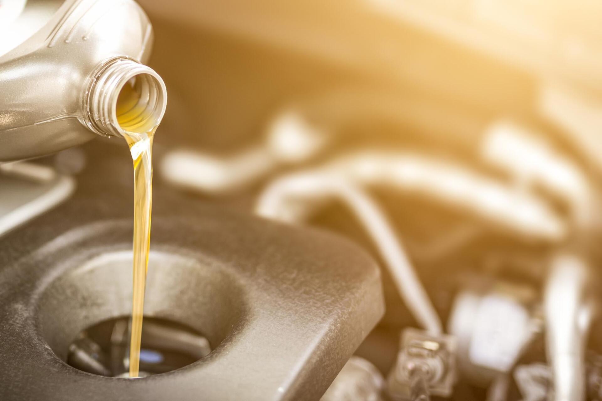 A bottle of oil is being poured into a car engine.