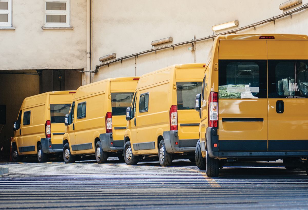 A row of yellow vans parked in front of a building.