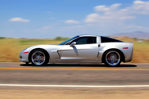 Silver sports car driving on a highway with a blurred desert background
