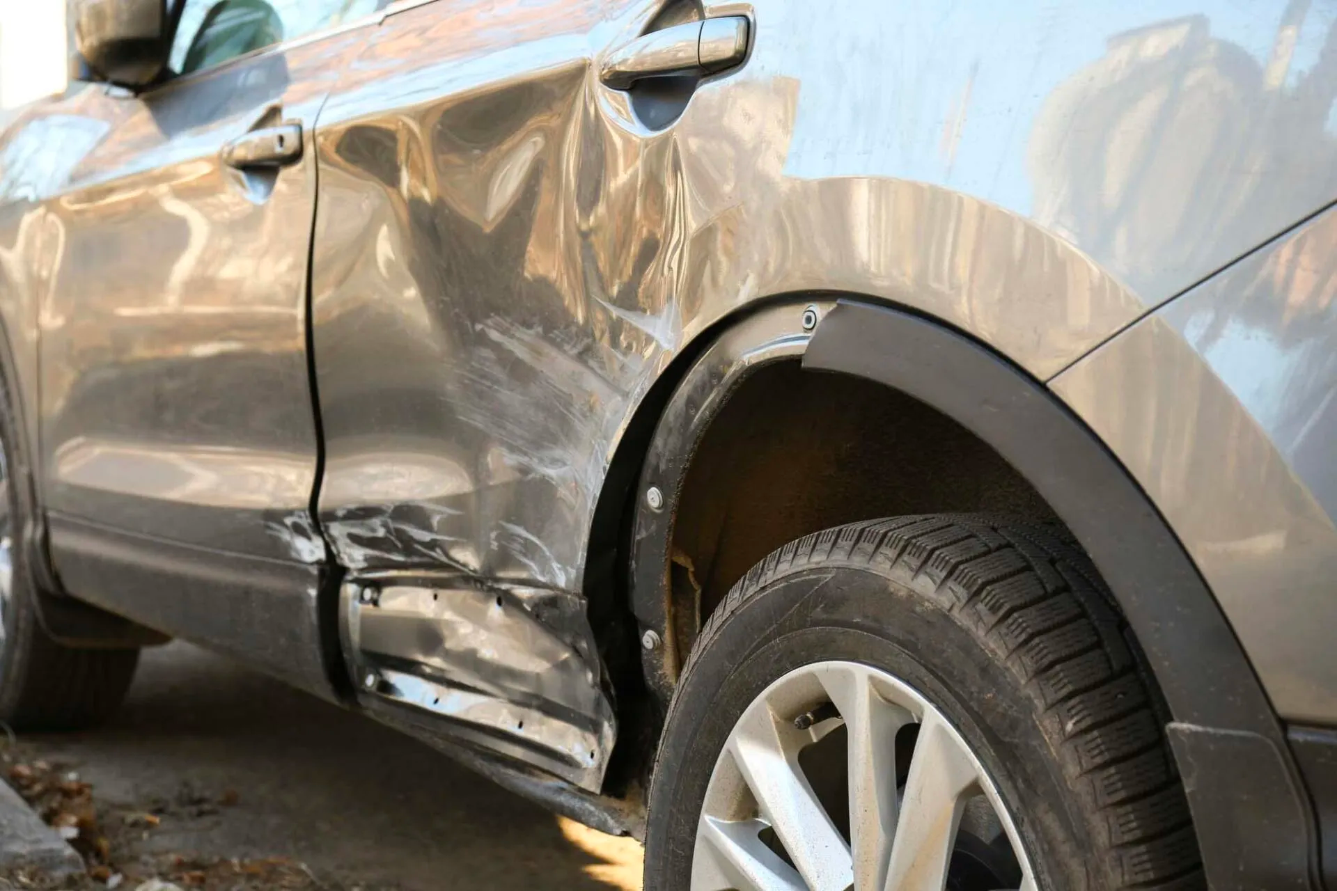 A car with a damaged side is parked on the side of the road.