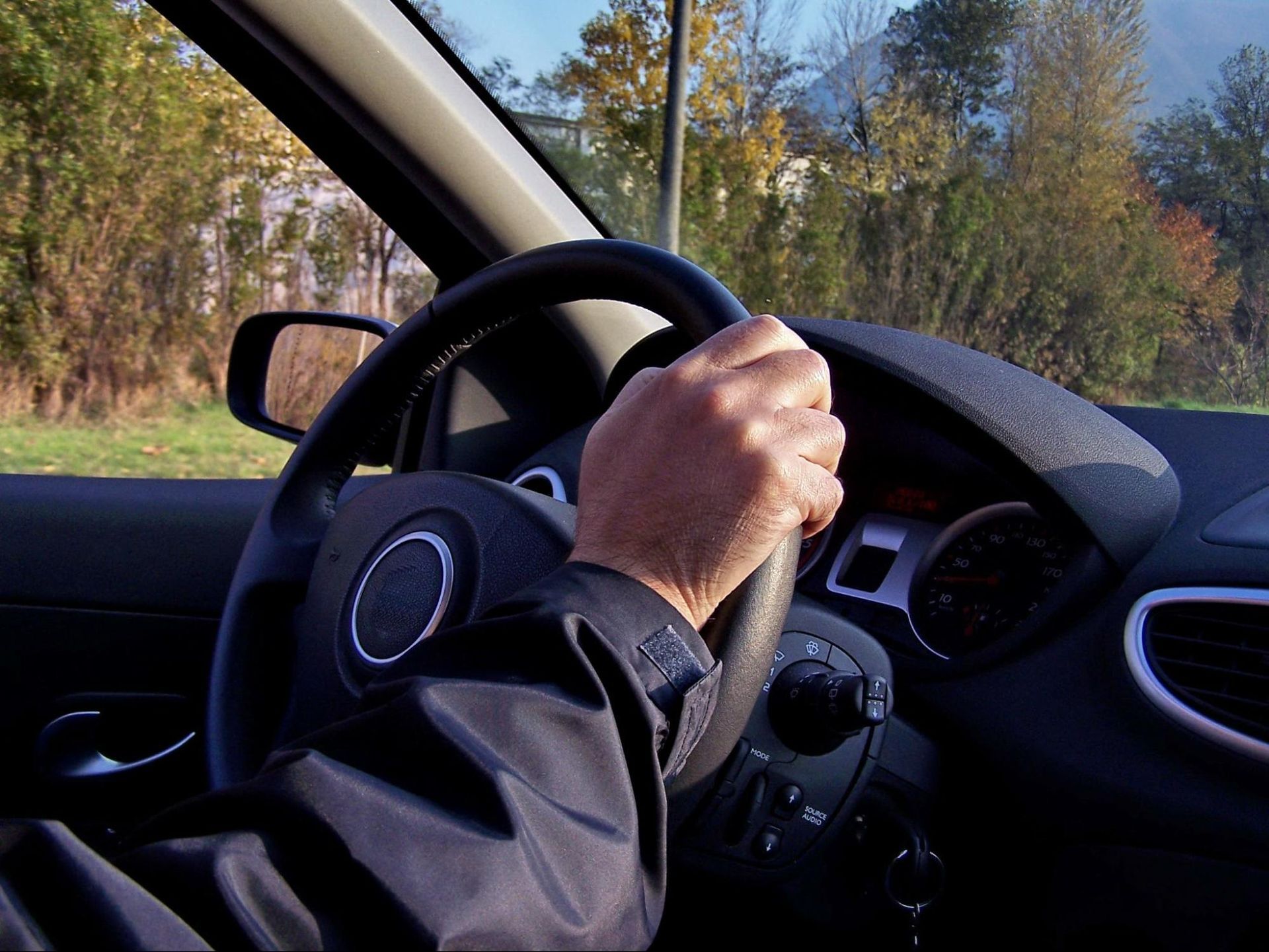 a man is driving a car with his hand on the steering wheel