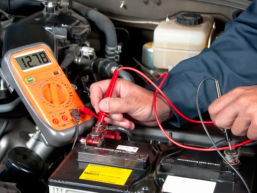A man is using a multimeter to test a car battery