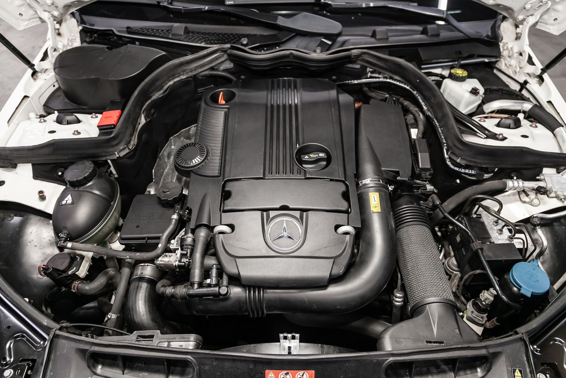 The engine of a white car is shown with the hood open.