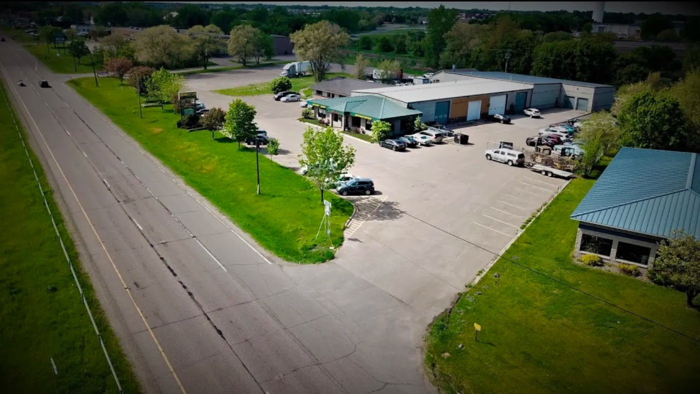 An aerial view of a parking lot next to a road and a building.