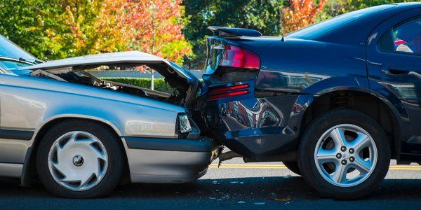 Two cars are involved in a car accident on the side of the road.