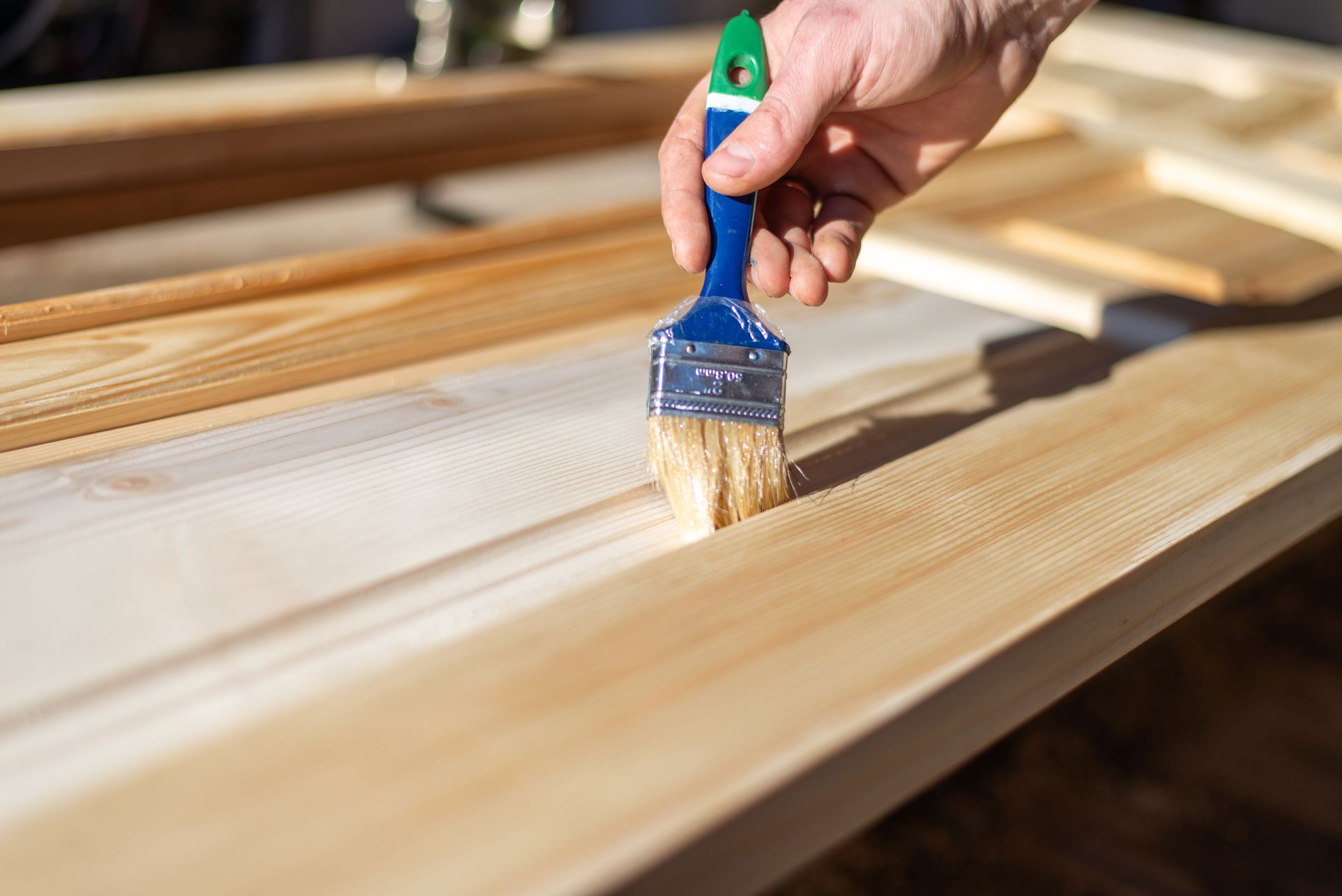 Hand brushing light-colored stain onto a wooden board during refinishing