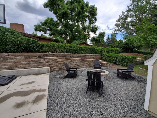 A fire pit with chairs and a basketball hoop in the background.