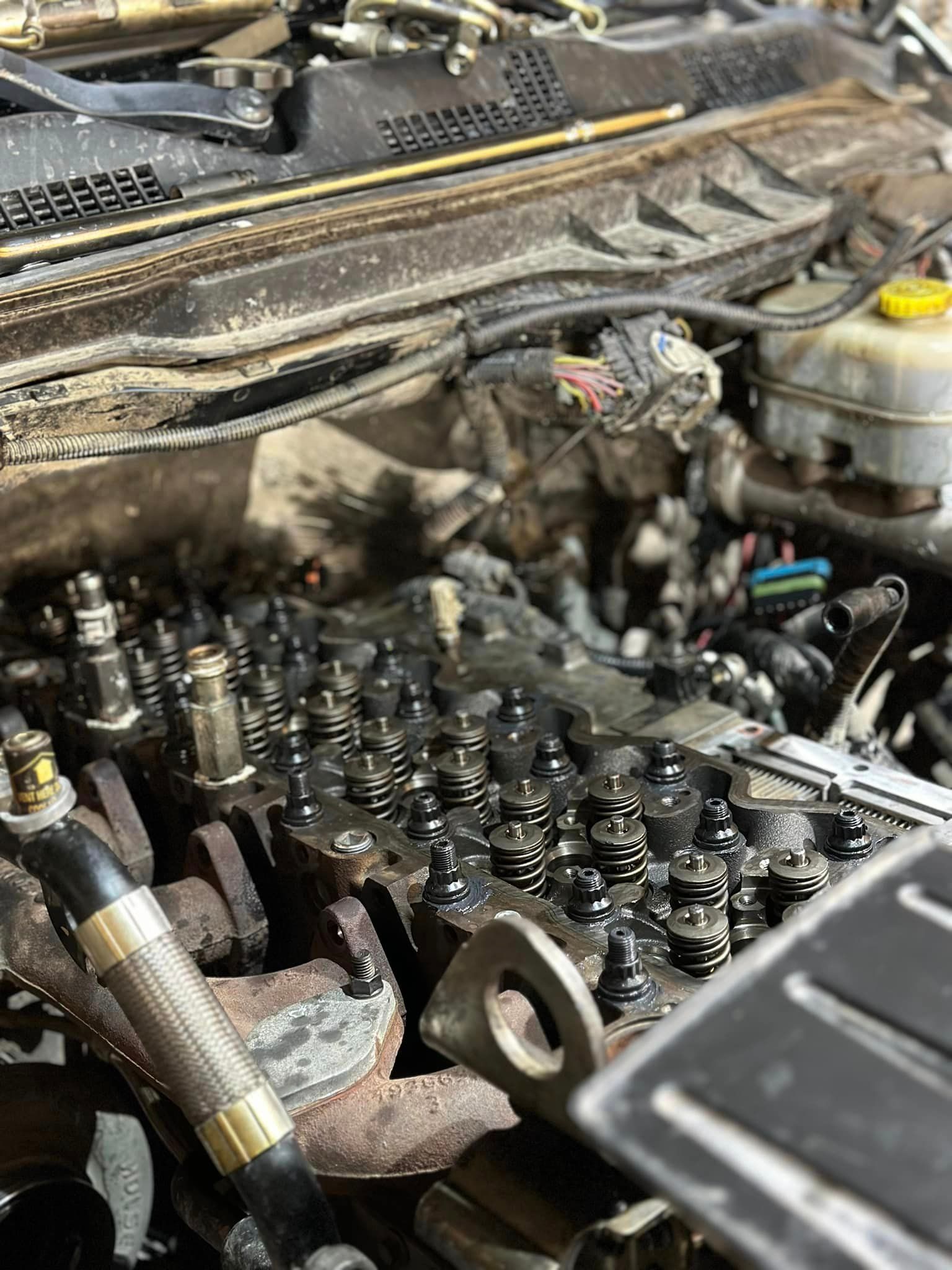 An open automotive engine with exposed valve springs, metal components, and wires, viewed from above.