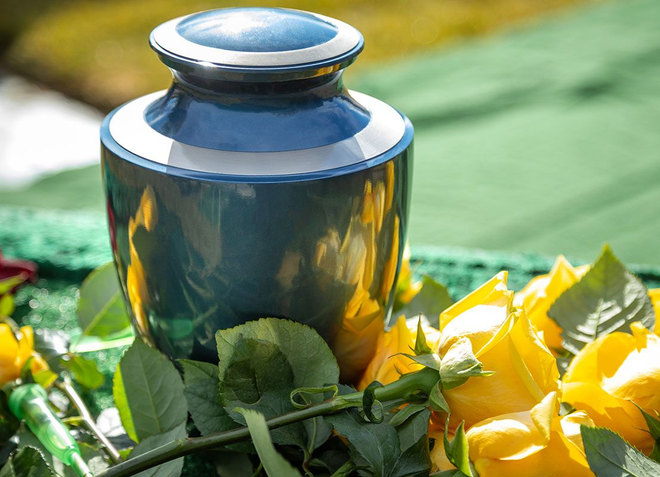 Blue vase among yellow flowers and green leaves on a cloth-covered surface