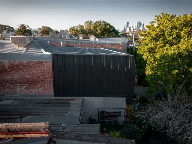 Rooftops with a dark gray facade, brick building, and city skyline in the distance.