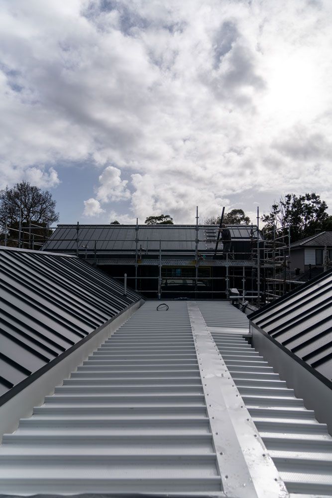 View of a partially constructed roof with scaffolding under a cloudy sky.