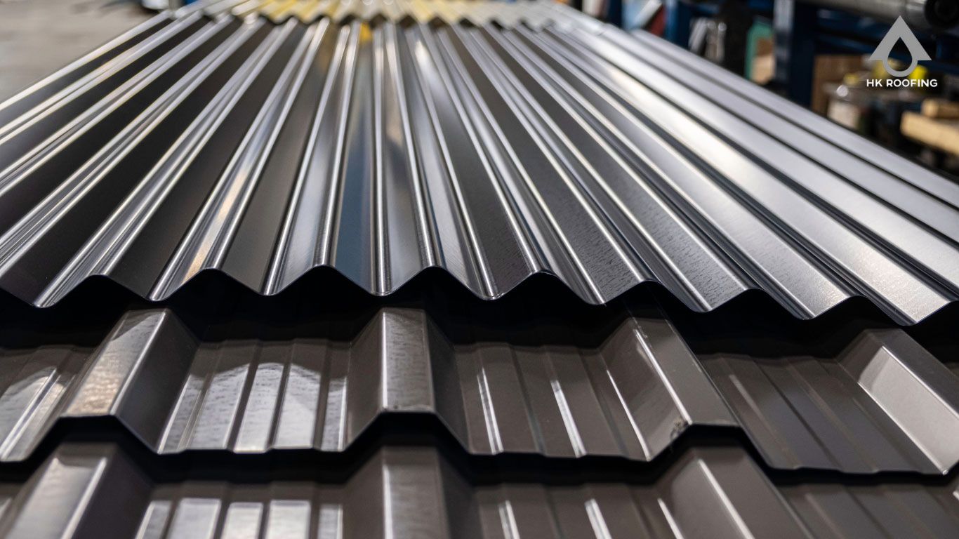 Close-up view of stacked corrugated metal roofing sheets in shades of gray.