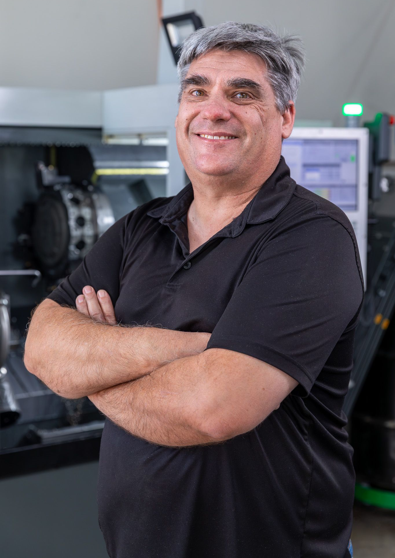 Jeff Davis of Precision Metal Craft with crossed arms smiling in a machine shop, machinery in background.
