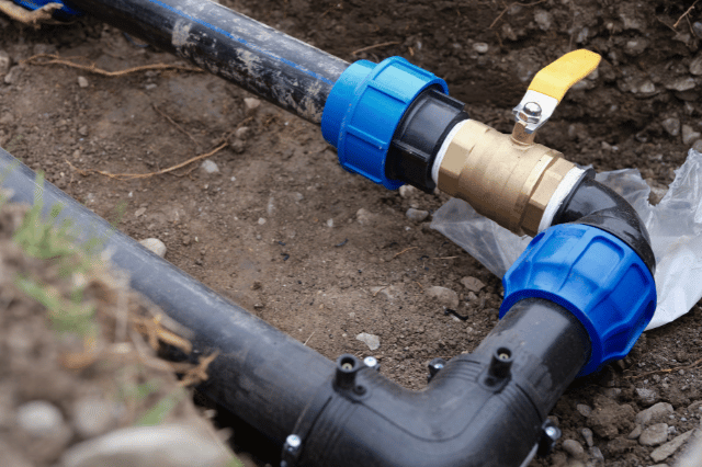 A close up of a water pipe being installed in the ground.