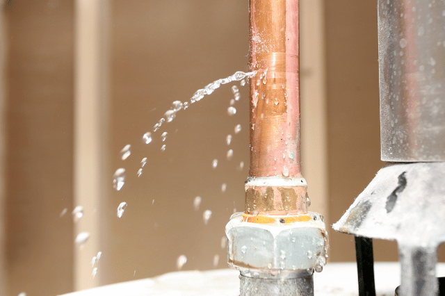 A copper pipe is leaking water and water is coming out of it.