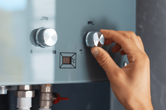 A person is adjusting the temperature of a water heater.