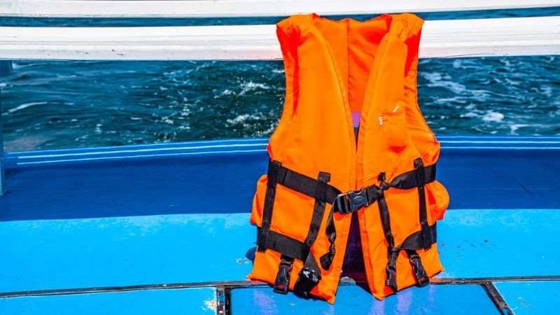 A life jacket is sitting on the side of a boat in the water.