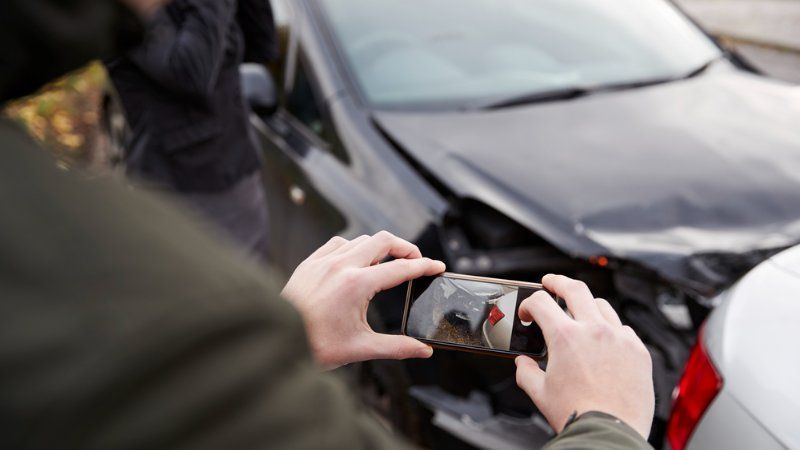 A person is taking a picture of a car accident with a cell phone.