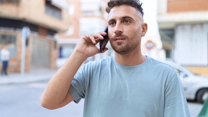 A man is talking on a cell phone on the street.