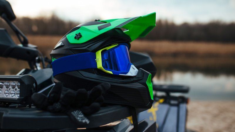 A helmet and goggles are sitting on the back of an atv.