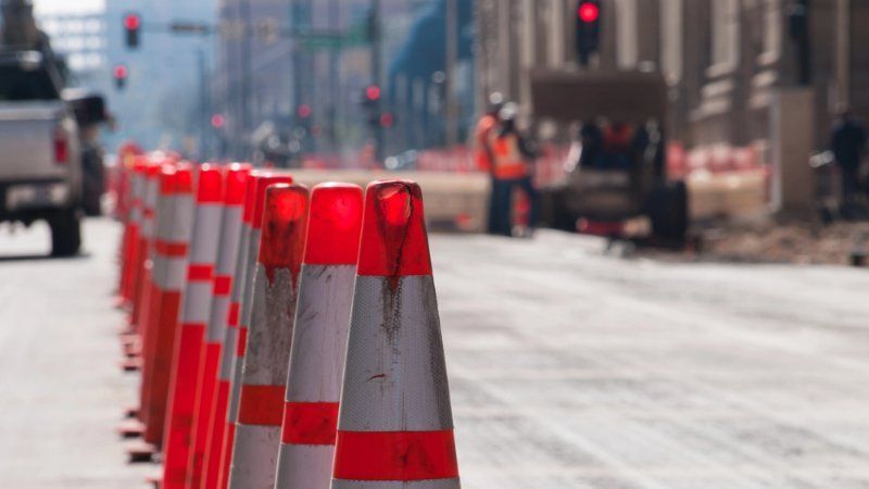 A row of orange and white traffic cones are lined up on the side of a street.