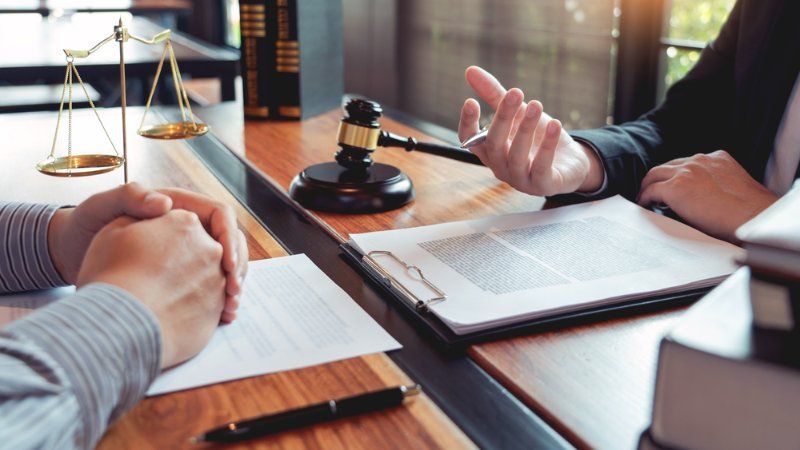 Two people are sitting at a table with papers and a judge 's gavel.