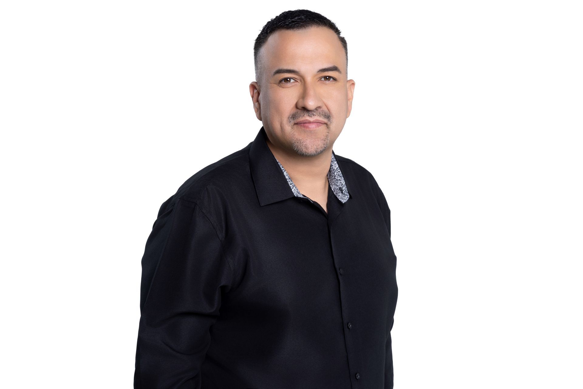 A person with a neutral expression wearing a black button-down shirt against a white background.