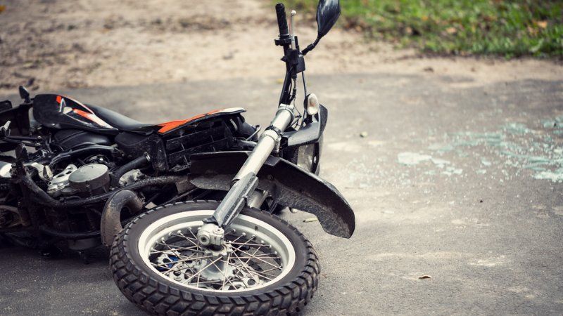 A damaged motorcycle lying on its side on an asphalt road.