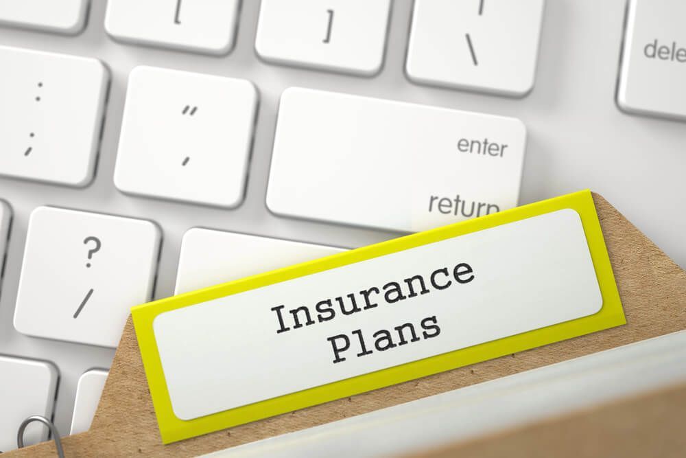 A computer keyboard with a folder labeled insurance plans