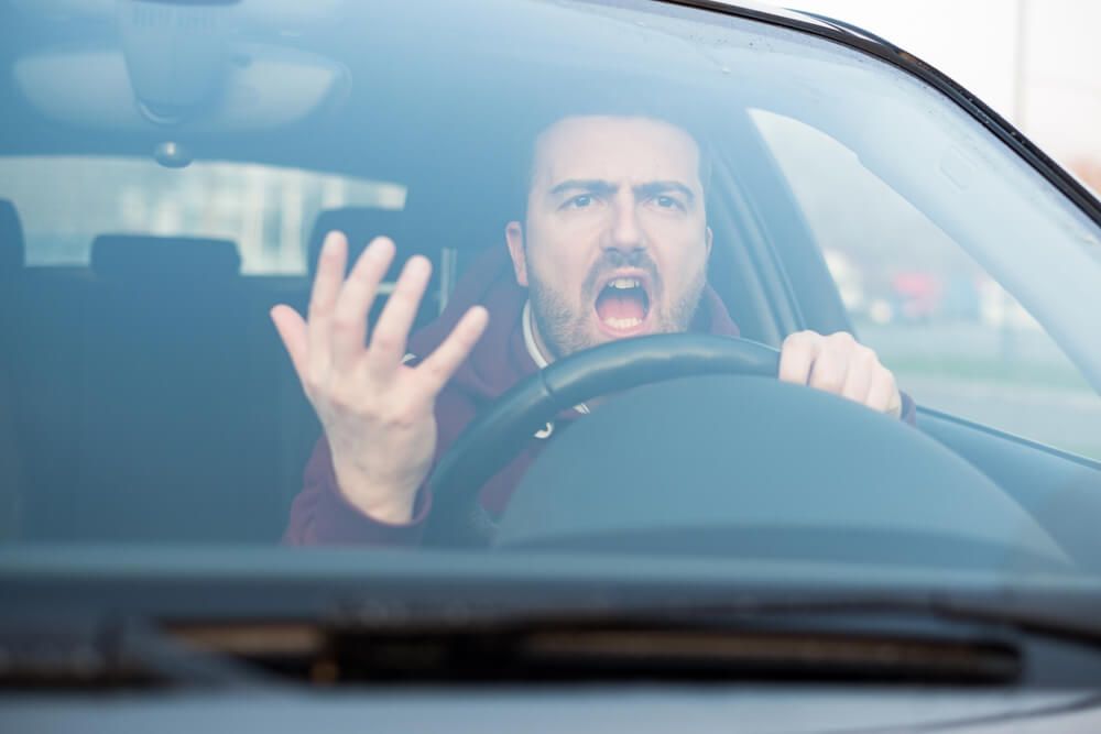 A man is driving a car and screaming.