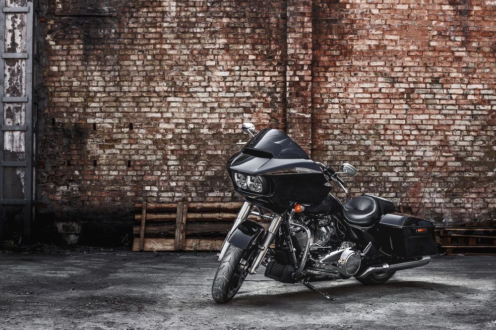 A black motorcycle is parked in front of a brick wall.