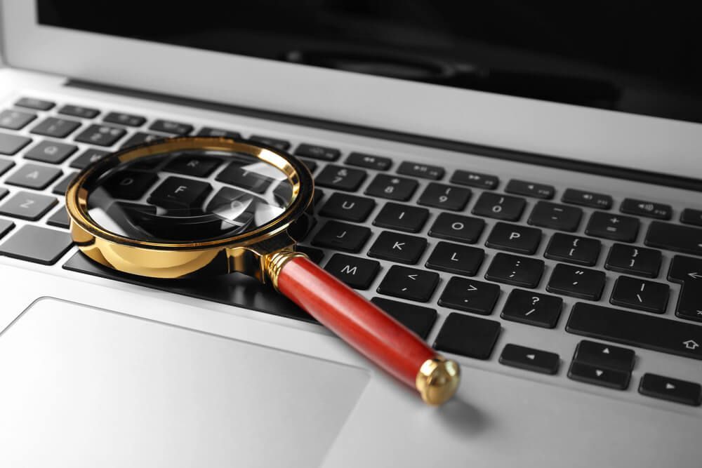 A magnifying glass is sitting on top of a laptop keyboard.