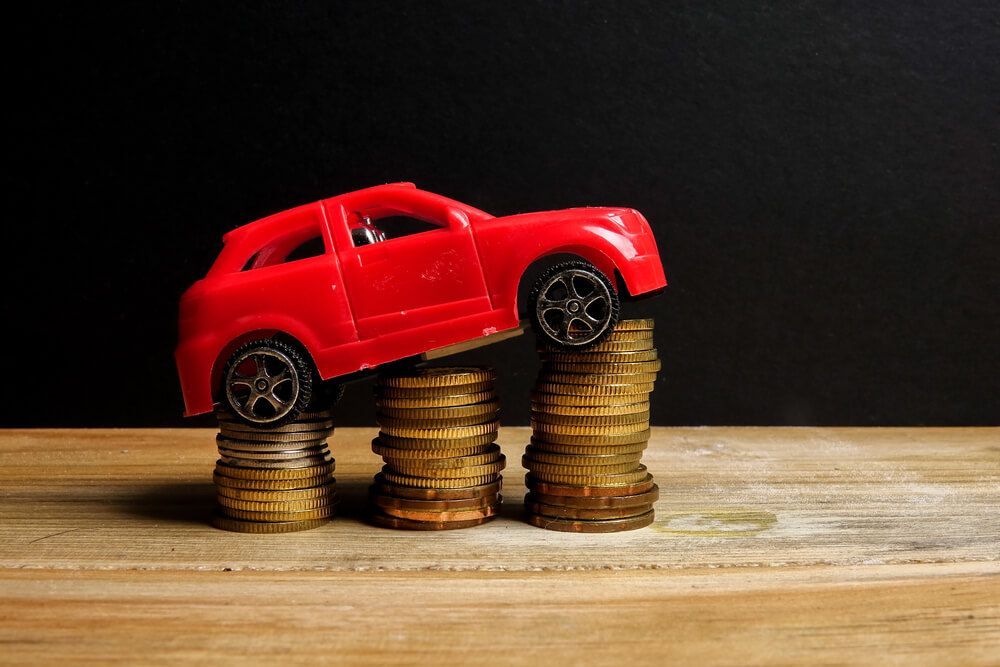 A toy car is sitting on top of a pile of coins.