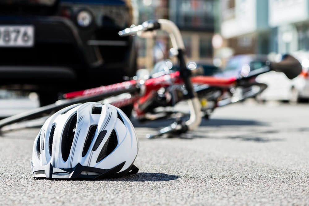 A helmet is laying on the ground next to a bicycle.