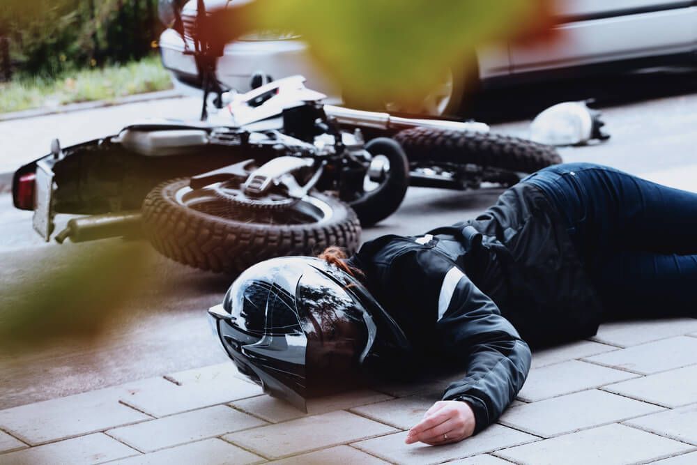 A person is laying on the ground next to a motorcycle.