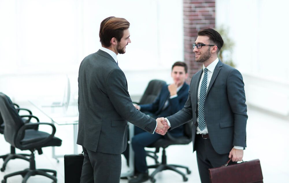Two businessmen are shaking hands in an office.