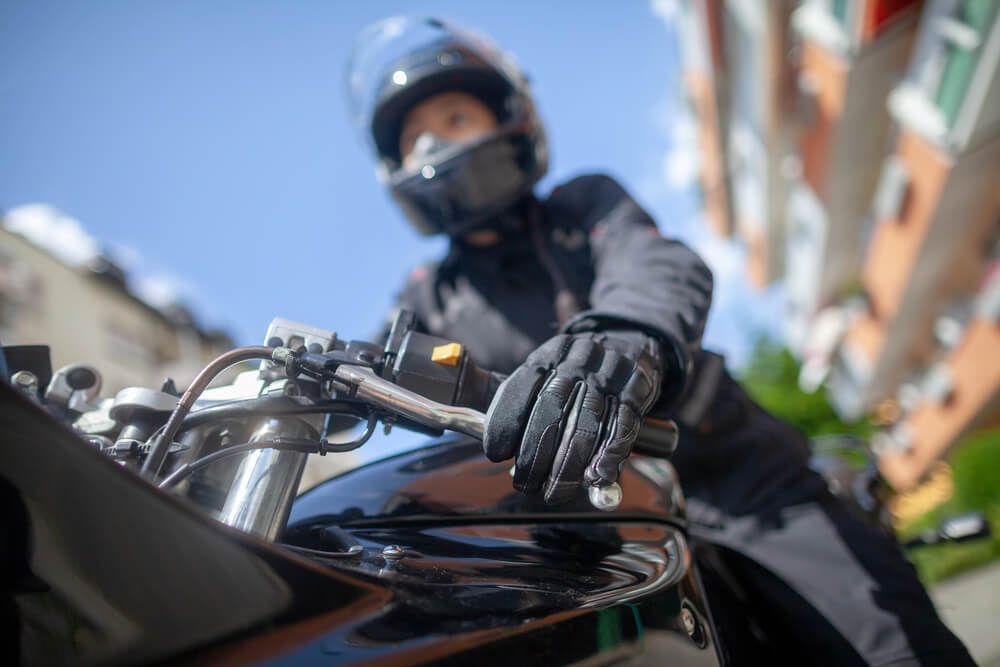 A man wearing a helmet and gloves is riding a motorcycle.