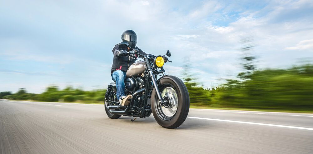 A man is riding a motorcycle down a road.